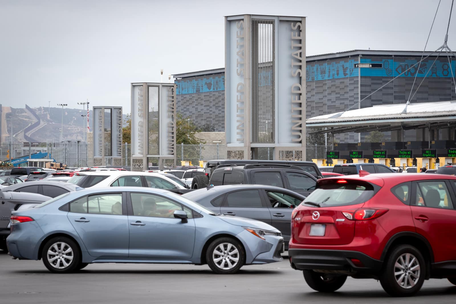 Cars queued at inspection booths beneath overhead lane signs at San Ysidro.